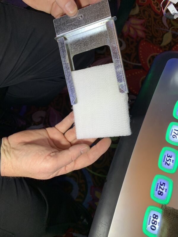 A person holding a 3M HAF Air filter for use with AGS and Cadillac Jack games in front of a slot machine.
