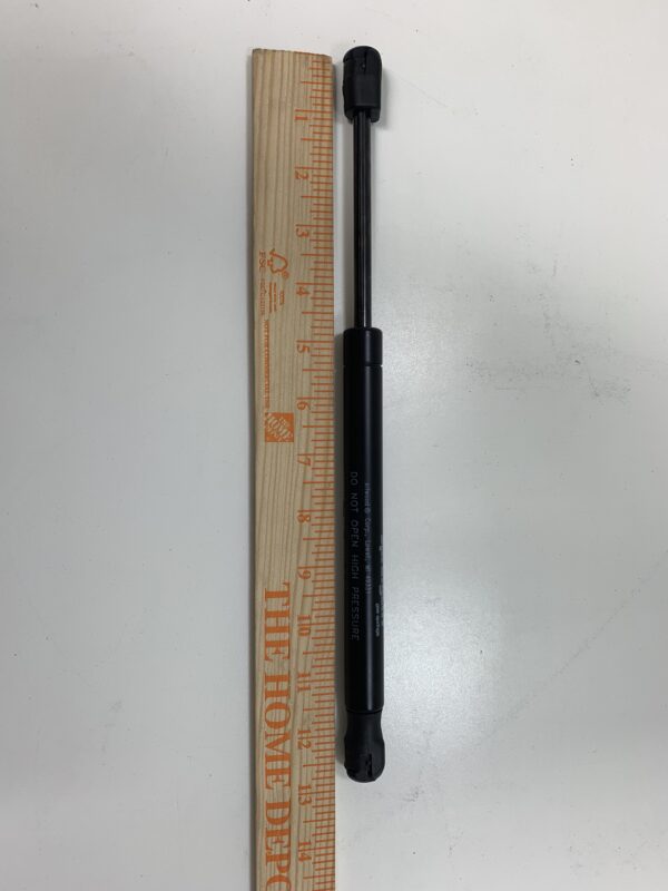 A Attwood Gas Spring (Shock) with a ruler and a tool next to it.