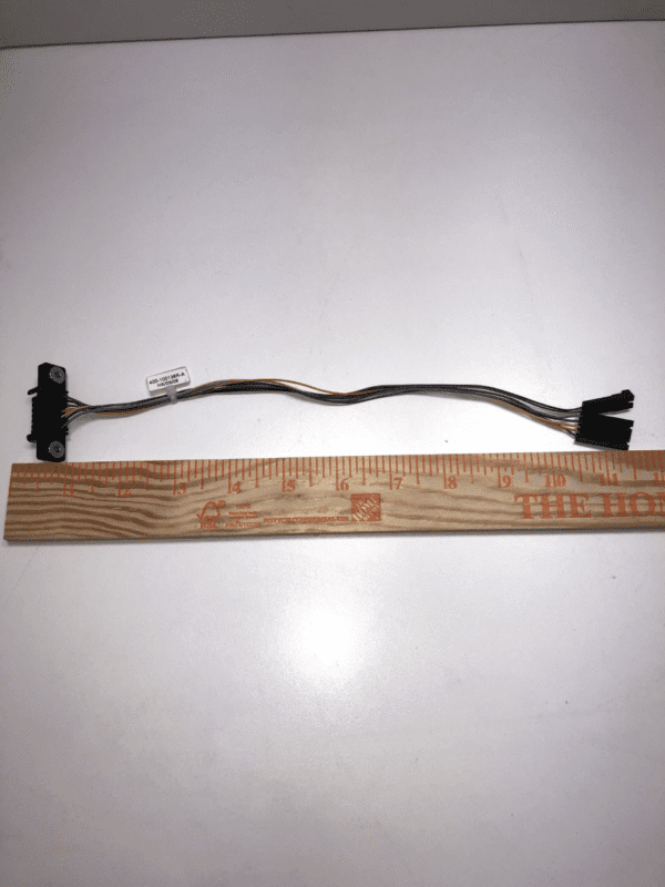 A black JCM Cable for WBA and UBA Bill acceptor with a ruler next to it.