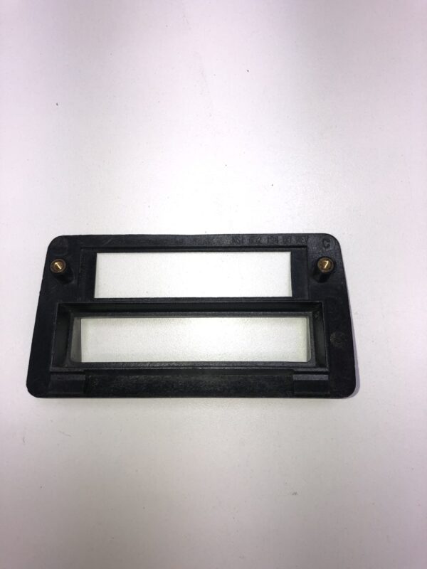 A BV Bezel with Connector black plastic cover for a door handle on a white surface.