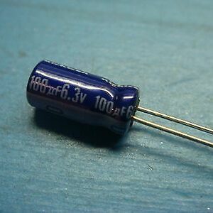 A 100uf 6.3v Nichicon Aluminum Electrolytic Capacitor - Radial Leaded on a blue surface.