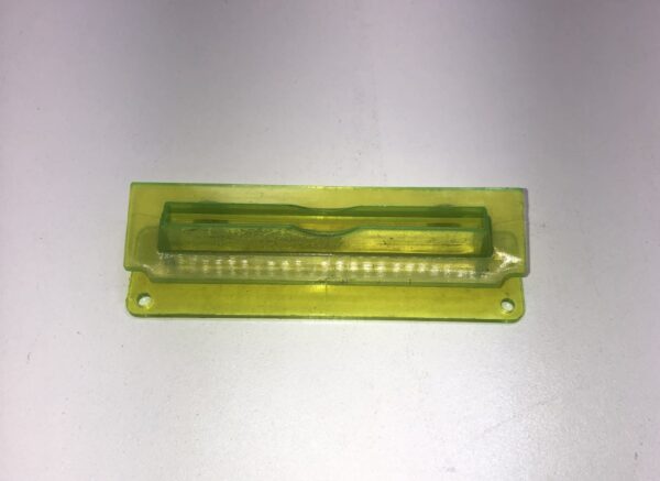 A yellow plastic Ticket Printer Bezel on top of a white surface. Limited availability, Legacy Part. New old Stock. GETT Part Ticket114