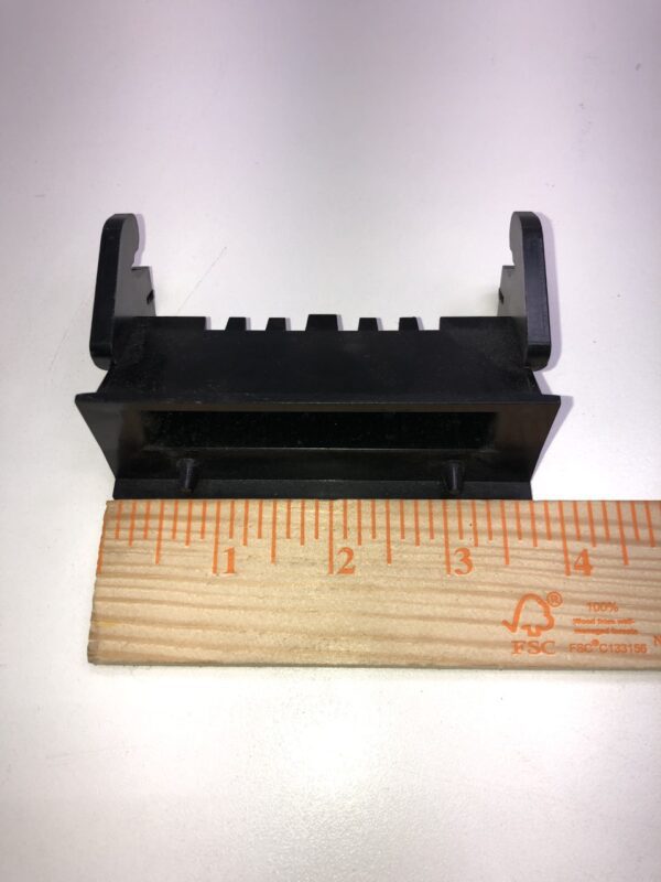 A black plastic Bill Validator Bezel for MEI BV Unit with a ruler next to it.