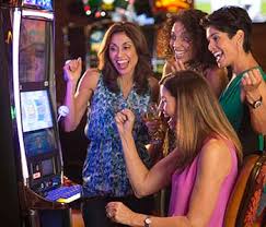 A group of women playing the IGT Crystal Core I Deck, Gold Panel-71931101 slot machines in a casino.