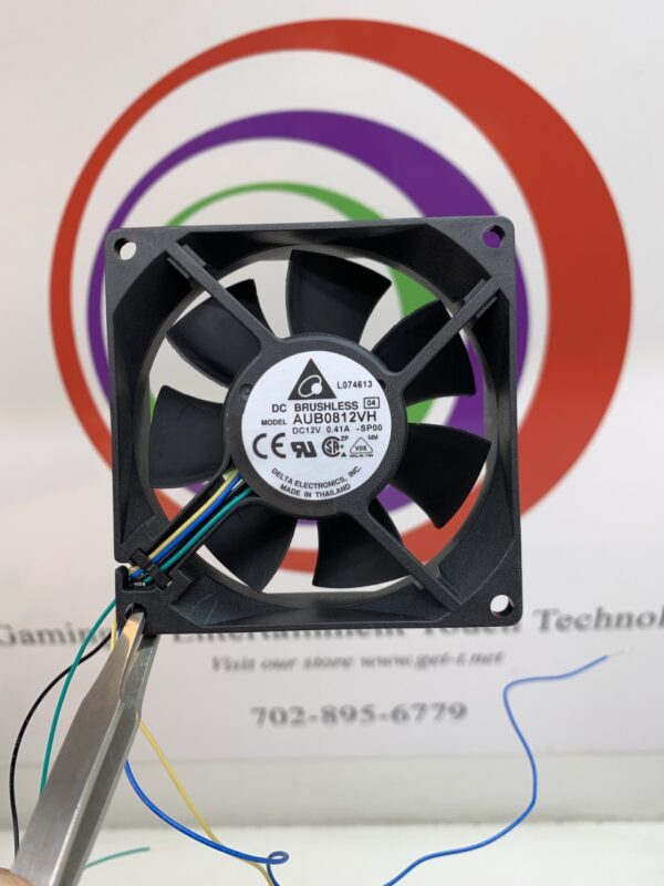 A person is removing a Cooling FAN, DELTA brand, AXIAL, BALL BEARING, 12VDC, 2.28W, .41A, 42.02 CFM, 3600 RPM, 80 X 80 X 25.4MM product from a computer.