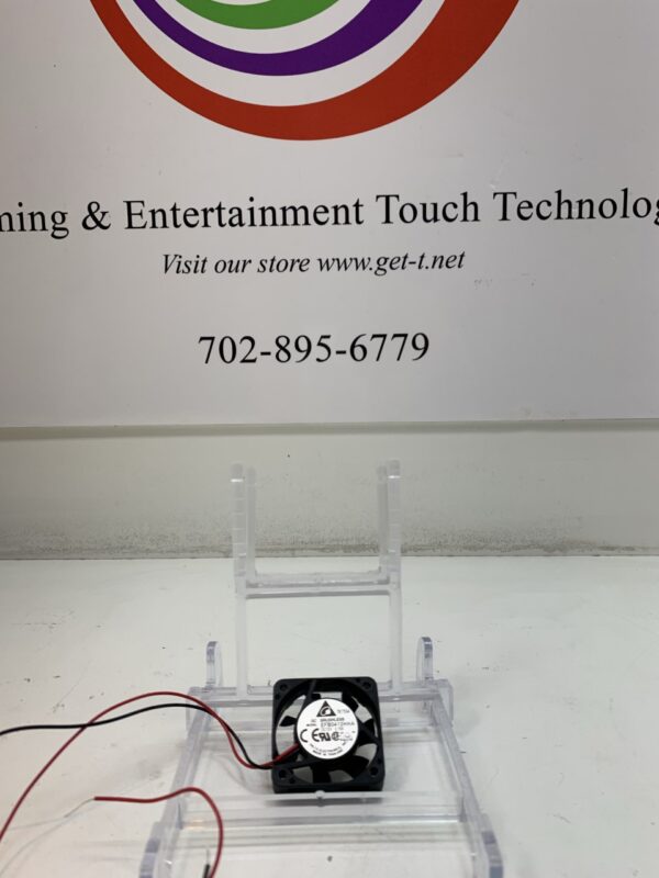A Cooling Fan- Delta Brand- Part # EFB0412HHA sits on a table next to a sign that says learning & entertainment touch technology.