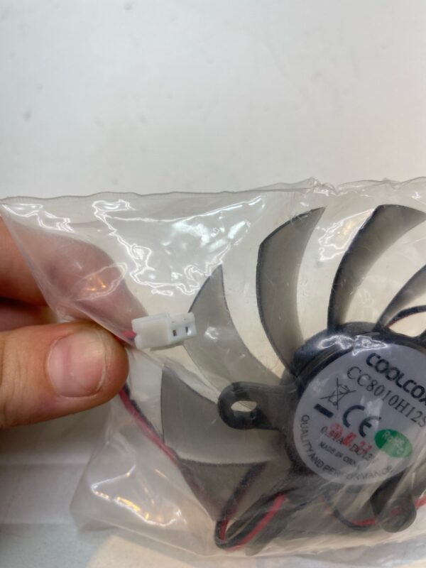 A person holding a 12V x .31A Cooling Fan in a plastic bag.