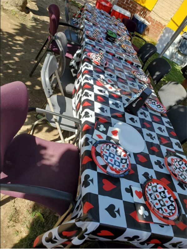 A table with a Poker Themed Birthday Party Decorations Casino Poker and Magic Plastic Tablecloth, 54 x 108 inches, Disposable Table Cover. GETT Part CQD104.