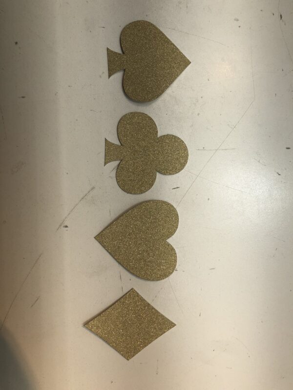 A set of Gold Glitter Card Suits - No-Mess Real Gold Glitter Cut-Outs - Las Vegas and Casino Party Confetti - Set of 24 on a table.
