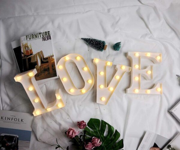 A bed with the LED Marquee Letter Lights 26 Alphabet Light Up Marquee Number Letters Sign for Wedding Birthday Party Battery Powered Christmas Lamp Night Light Home Bar Decoration (L) lighted up on it.