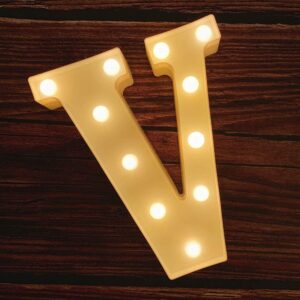 An LED Marquee Letter Light V on a wooden surface.