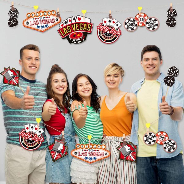 A group of people posing for a picture in front of a 24 Pieces Las Vegas Party Decorations, Casino Party Centerpiece Sticks Casino Cutouts for Baby Shower Birthday Party Casino Theme Party Centerpiece Sticks Table Toppers(Las Vegas) banner.