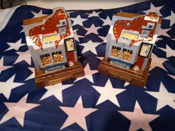 Two Harrah's 1997 Limited Edition Set Of Two Miniature Slot Machine Bookends on top of an american flag.