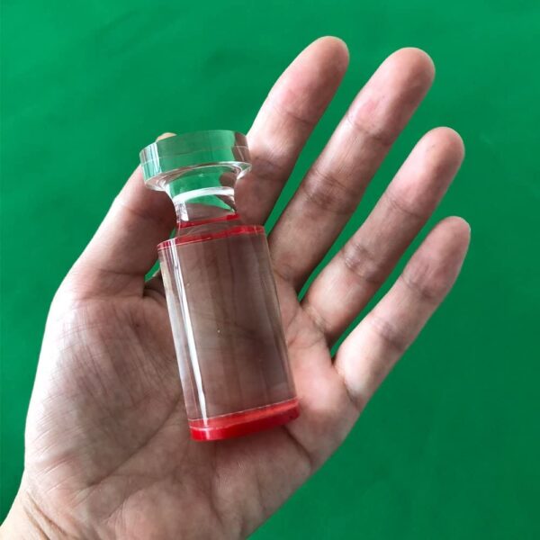 A hand holding a small glass bottle of Roulette Win Marker with red liquid in it, GETT Part CQT104.