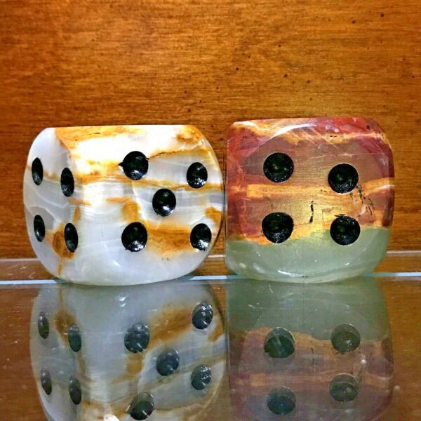 Two Large Carved Onyx Mid-Century Modern Dice Sculpture - Set of 2 sitting on top of a glass table.