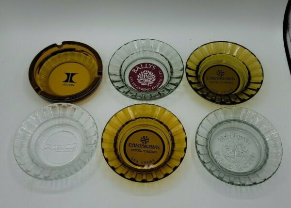 A group of Vintage Las Vegas Casino Ashtrays Bally's Castaways Peppermill Hilton with different logos on them.