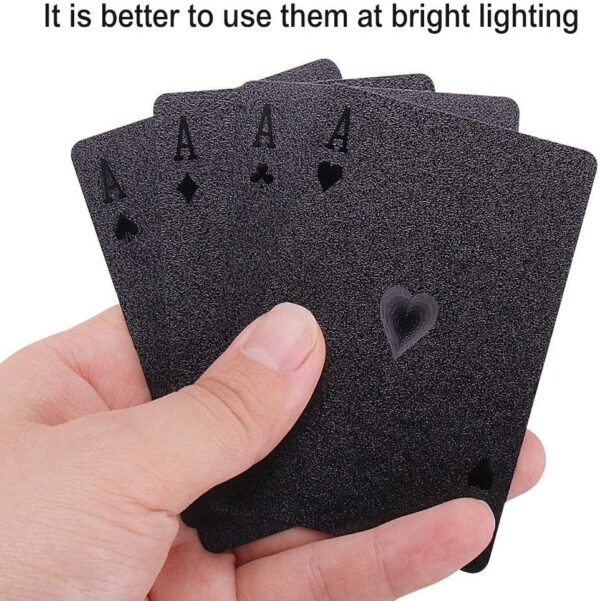 A hand holding four Joyoldelf Cool Black Foil Poker Playing Cards with the words it is better to use bright lighting.