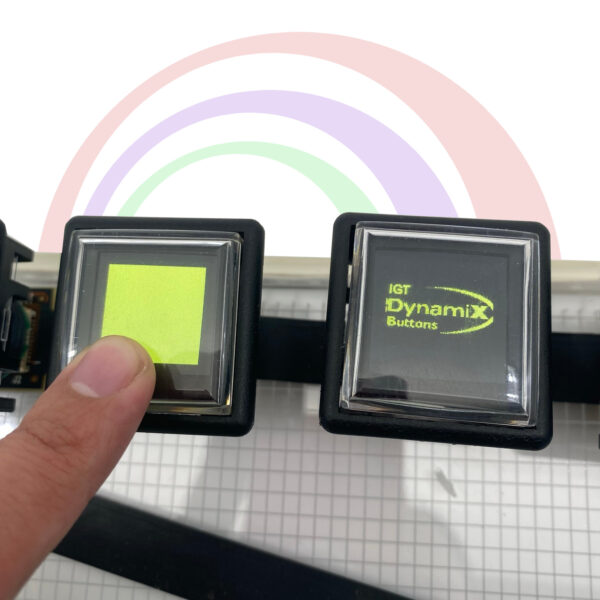 A person is holding an IGT Dynamic Button Tester GETT Part TESTERDYNAMIC100 with a rainbow on it.