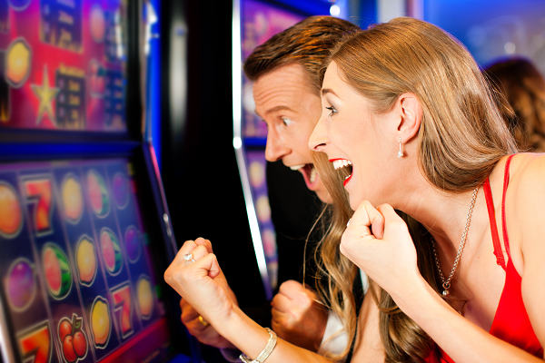A man and woman playing a slot machine featuring the GETT Part 3292H,27" PCap Touch Sensor for use with Helix + Games.