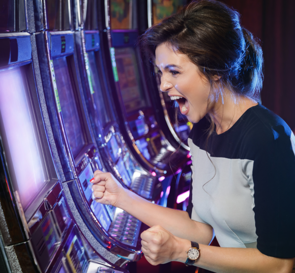 A woman excitedly celebrating a win at the 24" IGT Kortek LCD Topper for IGT Crystal Core in a casino.